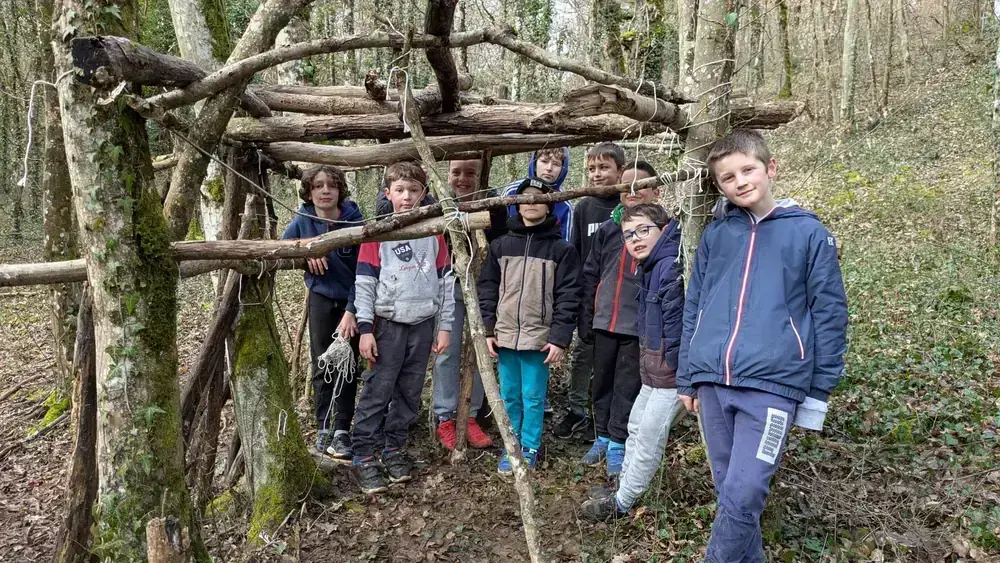 Groupe d'enfants dans une cabane en forêt pendant le stage multisports